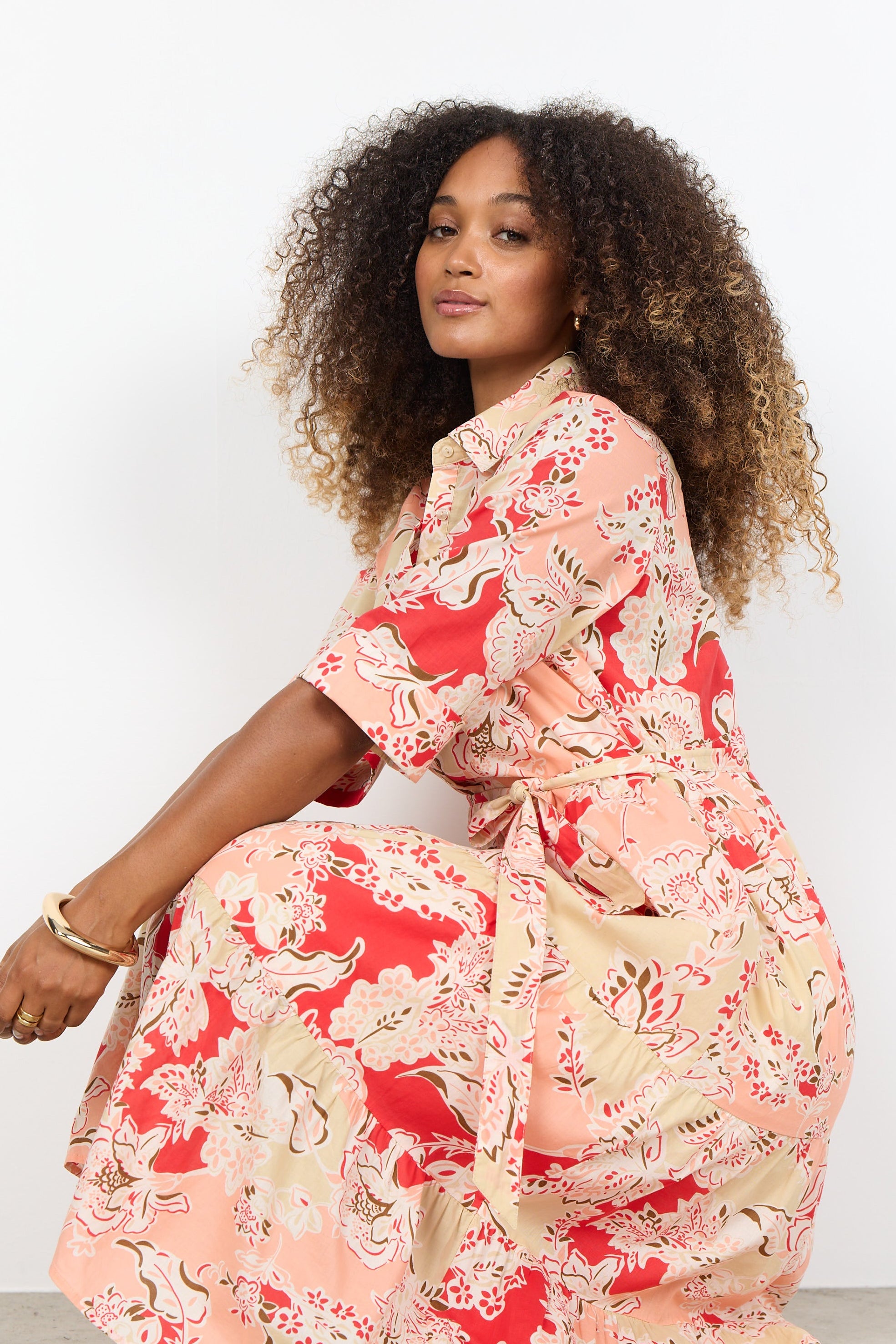 Woman wearing a floral dress sitting on a white background
